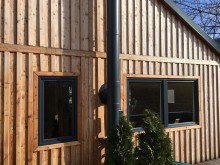 Gebäude aus Holz mit anthrazitfarbenen PVC-Fenstern